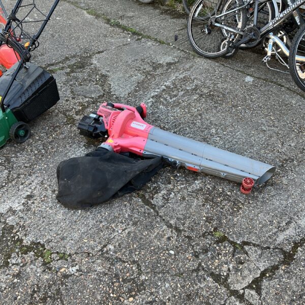 Used Eckman lawn vacuum with collection bag in a garden setting.