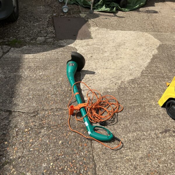 Used electric garden strimmer with a long handle and power cord.