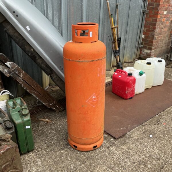 Large empty gas bottle outdoors, showing signs of wear.