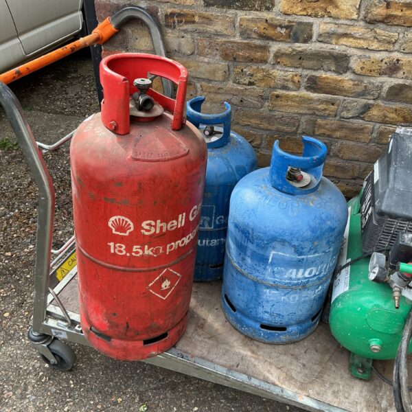 Lot of three empty gas bottles in red, blue, and green.