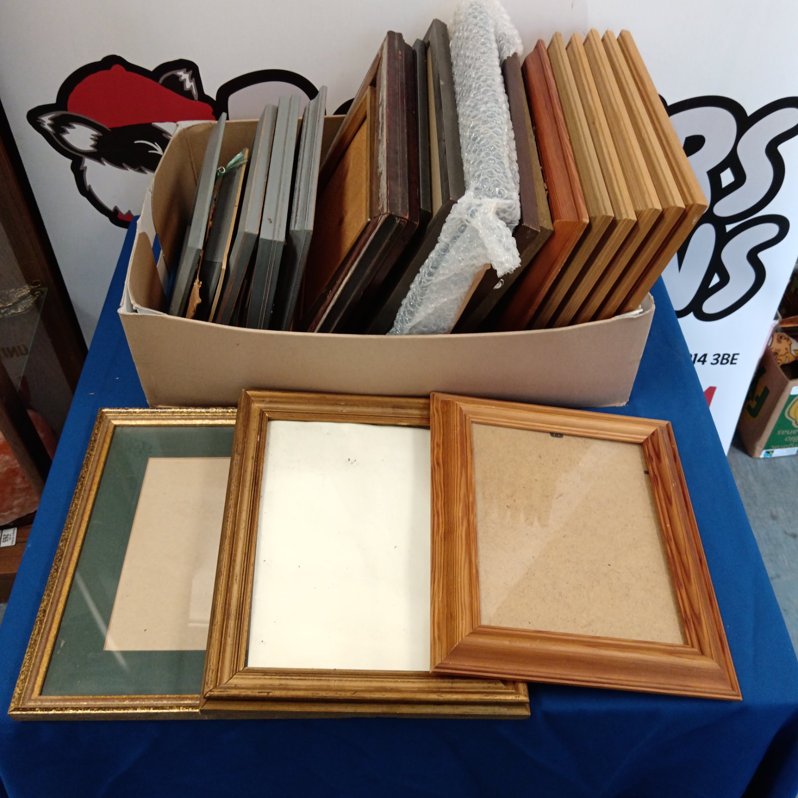 Assorted empty picture frames in a cardboard box.