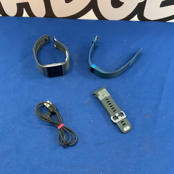Fitbit watch lot with charger and spare straps for fitness tracking.