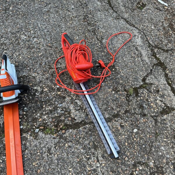 Flymo electric hedge trimmer with long blades for garden maintenance.