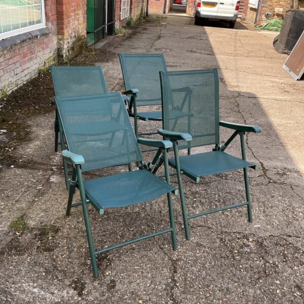 Four folding mesh garden chairs in a garden setting.