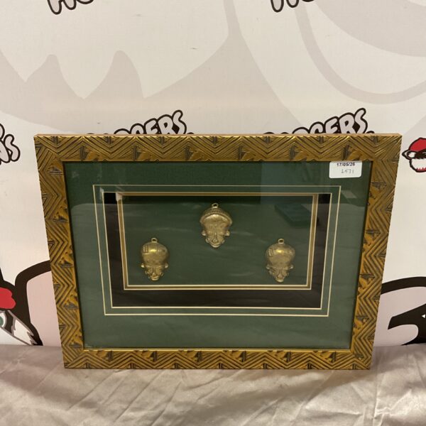 Framed set of three brass African masks for wall decor.