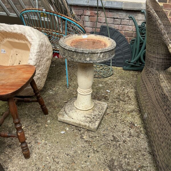 Stone effect garden bird bath in a garden setting.