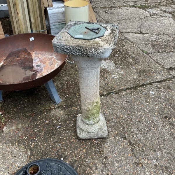 Weathered stone garden sundial with fluted pedestal.