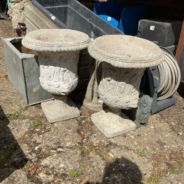 Pair of weathered stone garden urn planters for outdoor use.