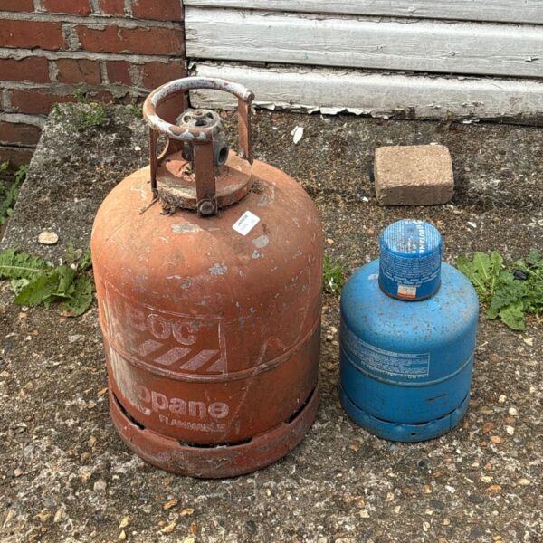 Two used gas bottles, a red BOC and a blue propane bottle.