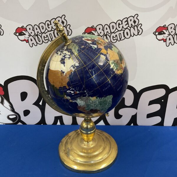 Antique gemstone globe on brass stand with visible crack.