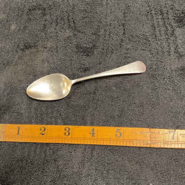 Antique Georgian silver spoon displayed with measuring ruler.