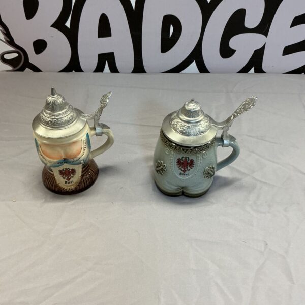 Detailed view of two vintage German beer tankards with painted designs.