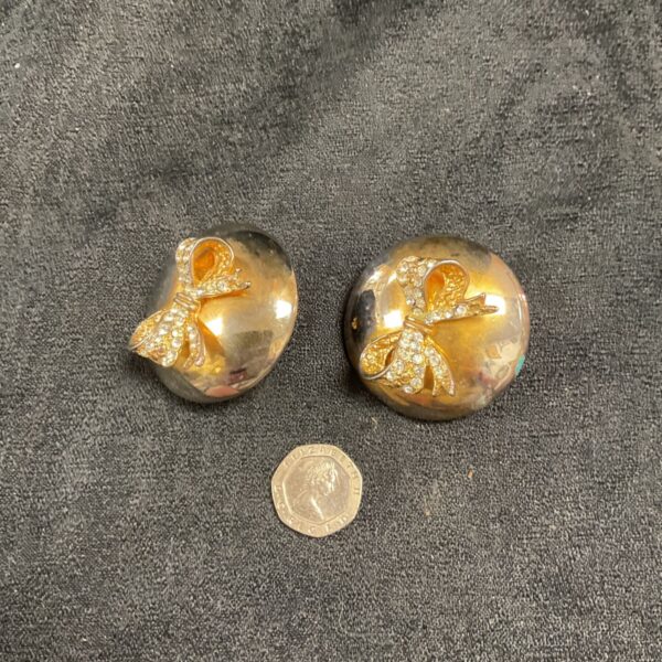 Large gilt clip-on earrings with a detailed floral design.