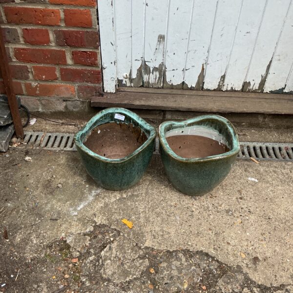 Two green glazed garden pots displayed outdoors.