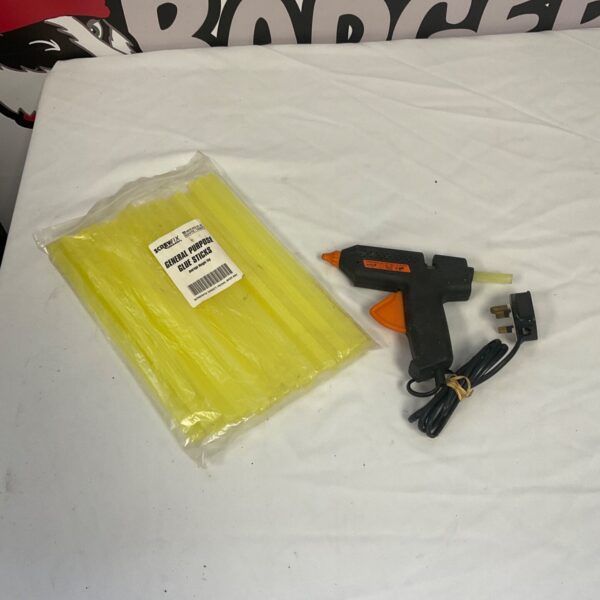 Electric glue gun with bag of glue sticks for crafting projects.