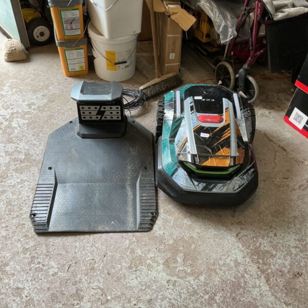 Go Robot lawnmower with charging base in a garage setting.