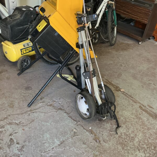 Folding golf trolley with a three-wheel design and handle.