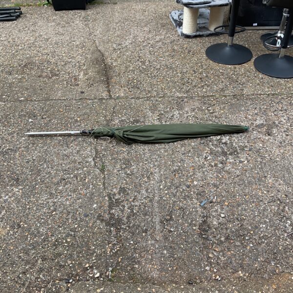 Green fishing umbrella for angling, showing signs of wear.