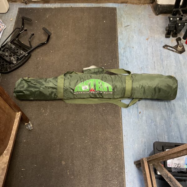 Green instant build tent folded for storage, ready for camping.