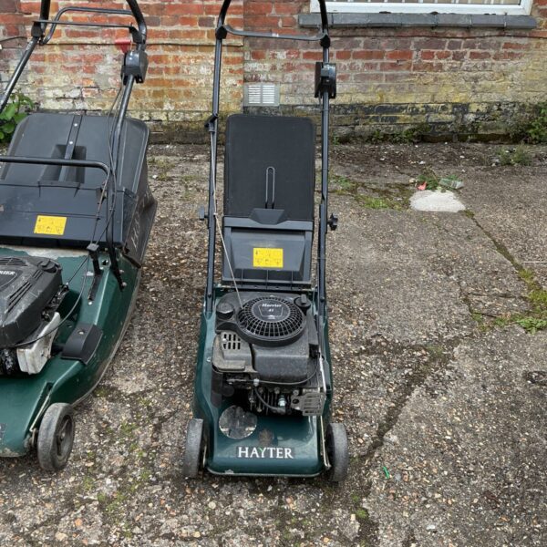 Green Hayter Harrier 41 petrol lawnmower in a garden setting.