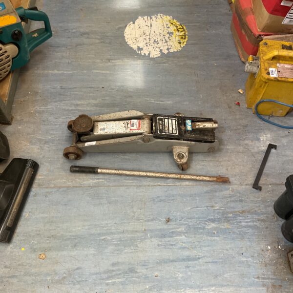 Side view of a used hydraulic trolley jack for car maintenance.