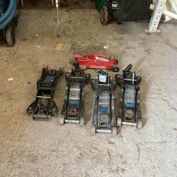 Lot of five hydraulic trolley jacks for vehicle repair.