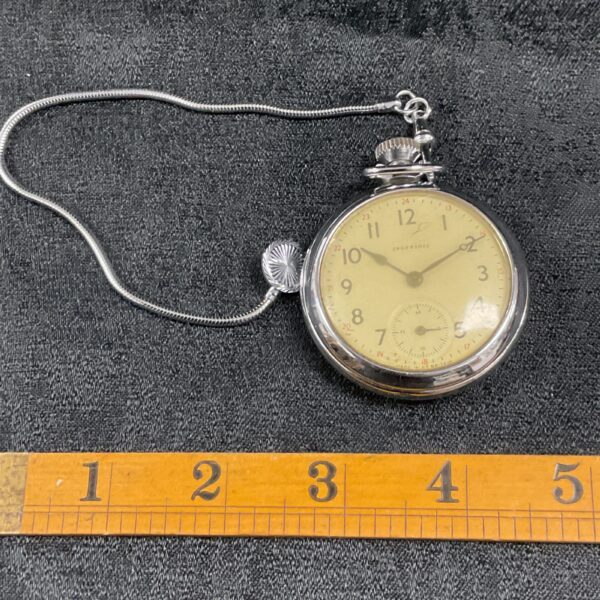 Vintage Ingersoll pocket watch with chain, detailed enamel dial.