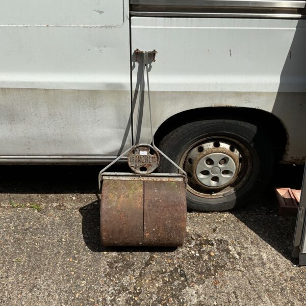 Vintage Ironcrete garden roller in a garden setting.