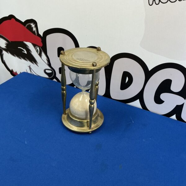 Large brass hourglass with sand flowing, vintage decorative timepiece.