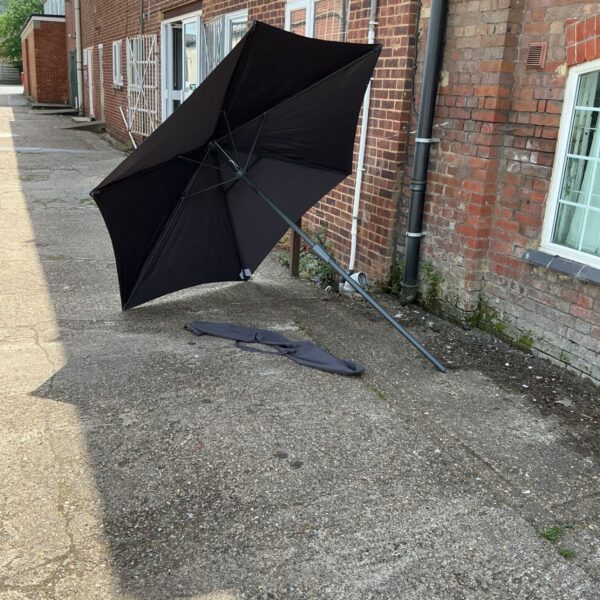 Large patio parasol with cover in a garden setting.