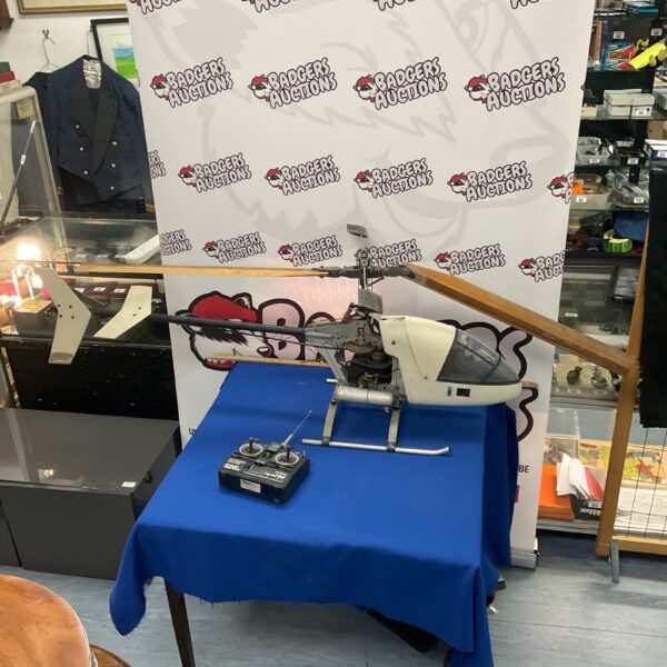 Large blue radio controlled helicopter with remote control presented on a table.