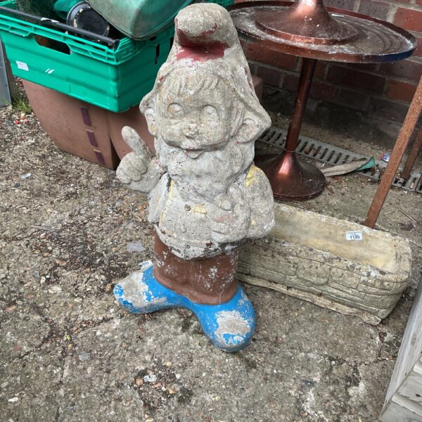 Large stone garden gnome in a garden setting.