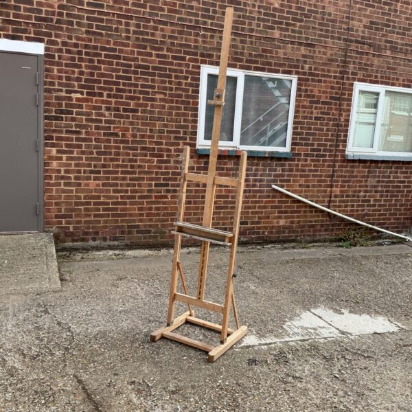 Large wooden artist easel standing outdoors.
