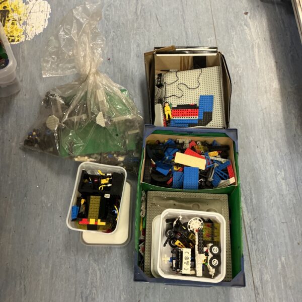 Assorted Lego kits and building blocks in a plastic storage box.