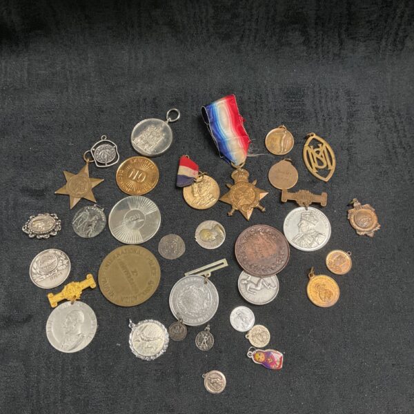Assorted vintage medals, badges, and coins in a collection.