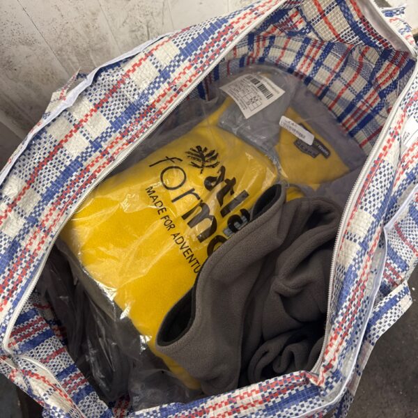 Top-down view of a lot of men’s fleece jackets in a woven bag.