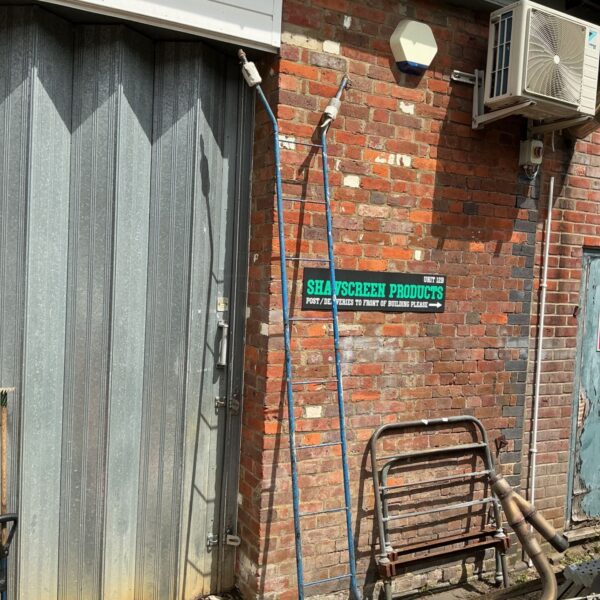 Metal adjustable ladder leaning against a brick wall.