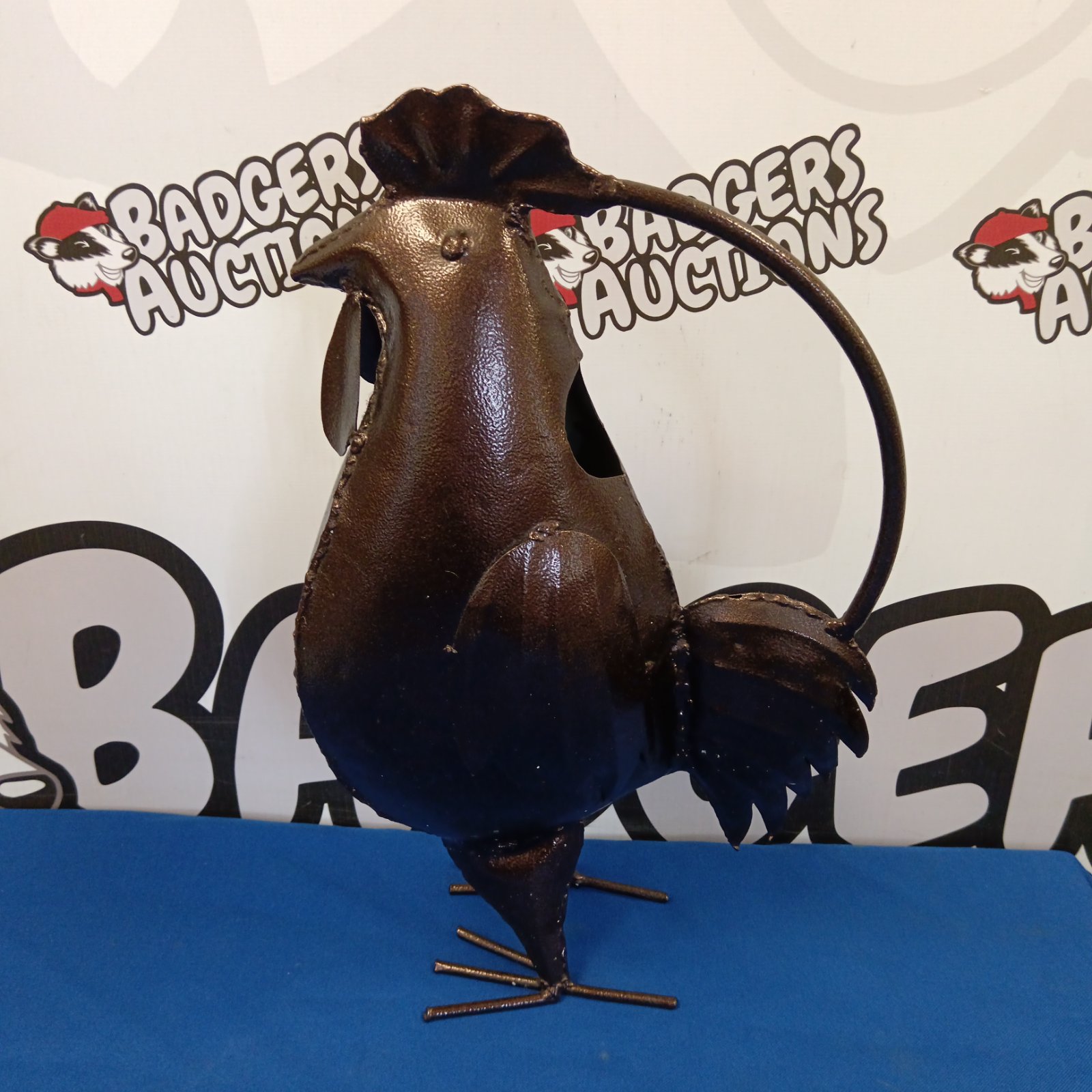 Dark metal cockerel watering can for garden decoration.