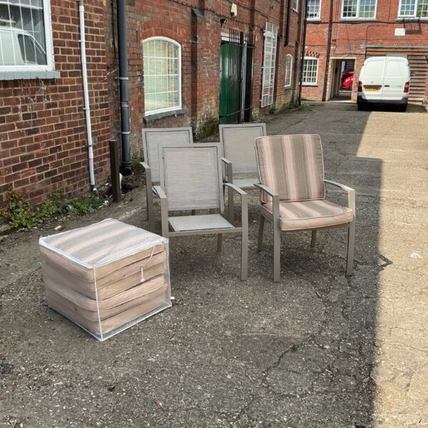Set of four metal garden chairs with cushions in a garden setting.