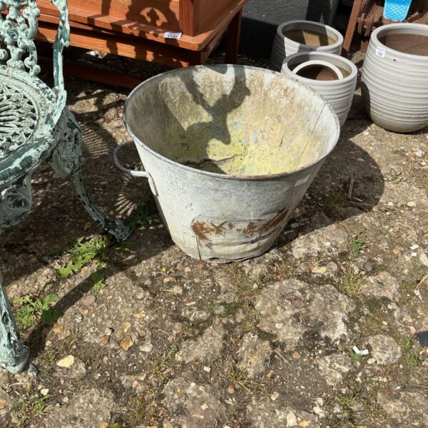 Weathered metal garden tub with rustic patina.