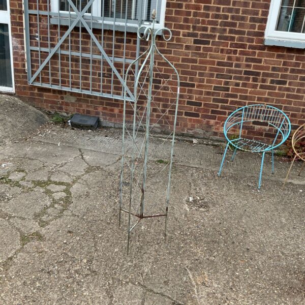 Vintage metal plant frame in a garden setting.