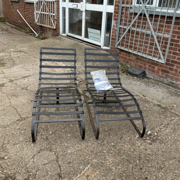 Pair of vintage metal sunloungers in a garden setting.