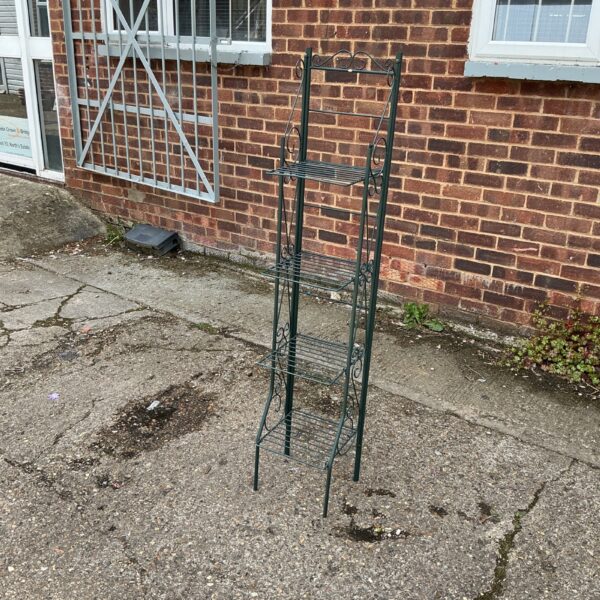 Metal tiered plant pot stand in a garden setting.