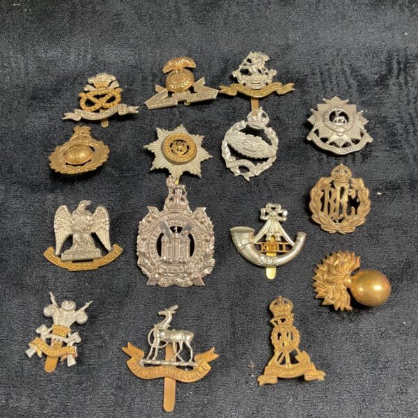 Collection of vintage British military cap badges on a dark background.