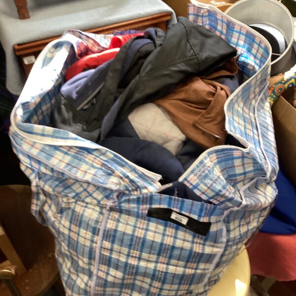 Large laundry bag filled with mixed clothing lot, coats and jackets.