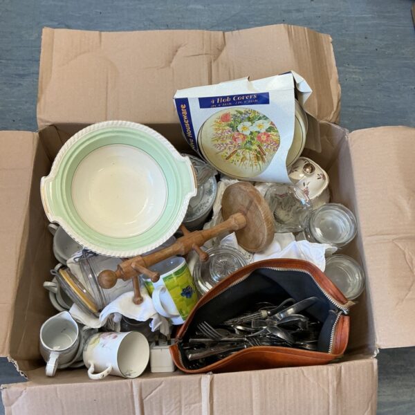 Mixed kitchenware lot with plates, bowls, and cutlery.