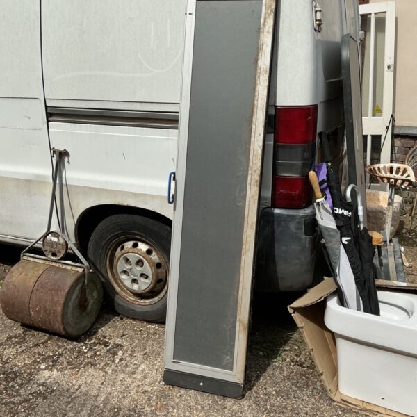 Aluminium mobility access ramp leaning against a van.