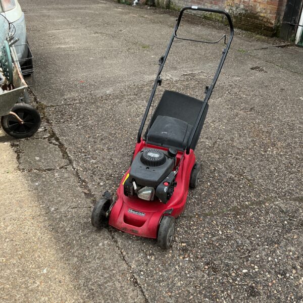 Red Mountfield RS100 petrol lawnmower in a garden setting.
