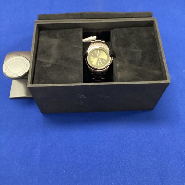 Navigator wristwatch presented in its original black case with charging dock.