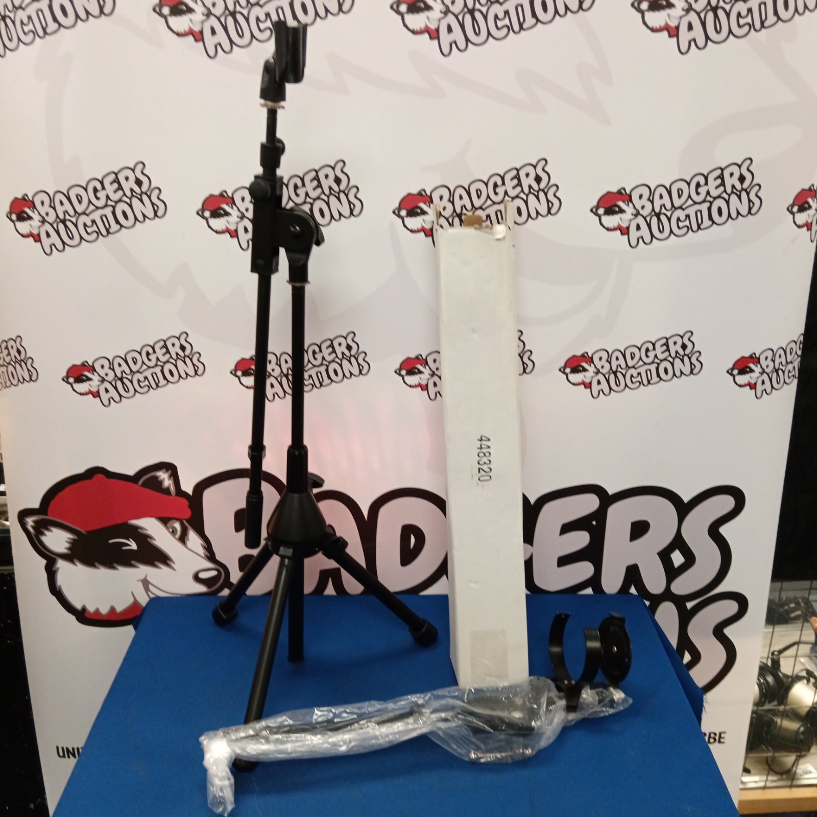 New microphone stand with black legs and silver microphone clip.